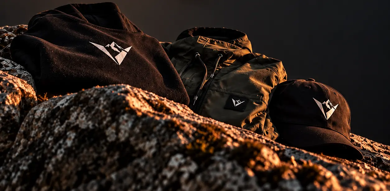 Buzo, campera y gorra Velkan sobre rocas